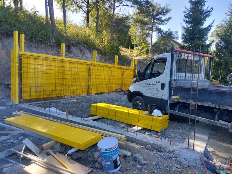 Banches de coffrage jaunes et ferraillage d'un mur en béton armé, camion de l'entreprise sur le chantier