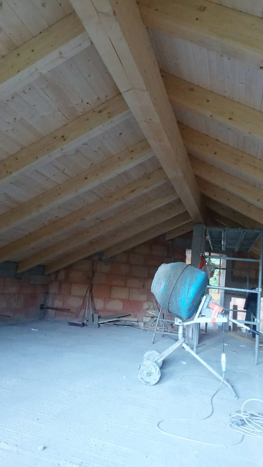Étage sous combles avec dalle en béton, murs en brique et bétonnière